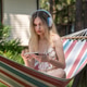 Caucasian girl 20 years old with headphones relaxing in a hammock and watching movie on mobile phone Caucasian girl 20 years old with headphones relaxing in a hammock and watching movie on mobile phone - PhotoDune Item for Sale