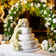Large wedding cake arranged on a table set up in the garden in the evening with decorative flowers Large wedding cake arranged on a table set up in the garden in the evening with decorative flowers - PhotoDune Item for Sale