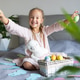 Smiling young girl sitting on bed holding colored eggs and stuffed bunny Smiling young girl sitting on bed holding colored eggs and stuffed bunny - PhotoDune Item for Sale