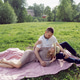 man and a woman in love in a dress and hat are sitting on a blanket on a green field under a tree man and a woman in love in a dress and hat are sitting on a blanket on a green field under a tree - PhotoDune Item for Sale