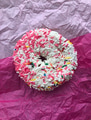 Overhead of a donut with lots of sprinkles on pink textured background. Overhead of a donut with lots of sprinkles on pink textured background. - PhotoDune Item for Sale