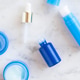 Flatlay skincare cosmetic products in blue and white packaging on white marble table Flatlay skincare cosmetic products in blue and white packaging on white marble table - PhotoDune Item for Sale