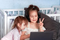 Two sisters learning online with laptop computer at bedroom. Two sisters learning online with laptop computer at bedroom. - PhotoDune Item for Sale