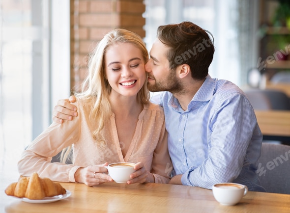 Handsome young guy kissing his girlfriend on romantic date at