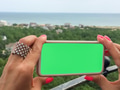 Gen Z holds mockup friendly mobile device with solid green screen for copy space text overlay Gen Z holds mockup friendly mobile device with solid green screen for copy space text overlay - PhotoDune Item for Sale