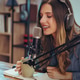 Woman recording podcast with microphone, headphones, and coffee at desk workspace Woman recording podcast with microphone, headphones, and coffee at desk workspace - PhotoDune Item for Sale