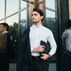 Young handsome man in jacket looking aside with bag for documents standing near glass building Young handsome man in jacket looking aside with bag for documents standing near glass building - PhotoDune Item for Sale
