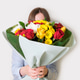 Young woman holding bouquet of flowers covering her face on a white background. Young woman holding bouquet of flowers covering her face on a white background. - PhotoDune Item for Sale