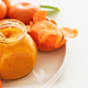 Glass jar of homemade marmalade with spoon and fresh tangerines on white table Glass jar of homemade marmalade with spoon and fresh tangerines on white table - PhotoDune Item for Sale