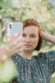 Young redhaired woman wear casual dress using smartphone for making selfie. Young redhaired woman wear casual dress using smartphone for making selfie. - PhotoDune Item for Sale