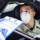 Driver wearing protective N95 face mask sitting by left drive wheel in UK drive-thru test centre Driver wearing protective N95 face mask sitting by left drive wheel in UK drive-thru test centre - PhotoDune Item for Sale