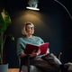 Middle aged woman reading book in scandy style hygge dark interior home. Lady dreaming Middle aged woman reading book in scandy style hygge dark interior home. Lady dreaming - PhotoDune Item for Sale
