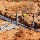 Construction site shows underground pipes being installed in a trench during a sunny day Construction site shows underground pipes being installed in a trench during a sunny day - PhotoDune Item for Sale