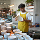 Young man in yellow apron inspecting a ceramic bowl in a tableware store Young man in yellow apron inspecting a ceramic bowl in a tableware store - PhotoDune Item for Sale