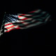 American flag emerging from the darkness with light shining on United States stars and stripes American flag emerging from the darkness with light shining on United States stars and stripes - PhotoDune Item for Sale