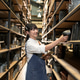 Young woman in apron scanning items on shelves with a handheld scanner and tablet Young woman in apron scanning items on shelves with a handheld scanner and tablet - PhotoDune Item for Sale