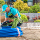 Gardener Working With Blue Tubing in a Landscaped Area Gardener Working With Blue Tubing in a Landscaped Area - PhotoDune Item for Sale