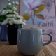 Close up of a coffee or tea mug on wooden table having blurred image of roses vase in background Close up of a coffee or tea mug on wooden table having blurred image of roses vase in background - PhotoDune Item for Sale
