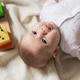 newborn baby is playing with educational toys lying on the floor on a gray linen blanket. top view newborn baby is playing with educational toys lying on the floor on a gray linen blanket. top view - PhotoDune Item for Sale