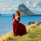 A woman in old-fashioned clothes stands with Tindholmur in the background. Vagar, Faroe Islands A woman in old-fashioned clothes stands with Tindholmur in the background. Vagar, Faroe Islands - PhotoDune Item for Sale