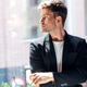 Handsome businessman thinking while looking forward standing next to the window at the office. Handsome businessman thinking while looking forward standing next to the window at the office. - PhotoDune Item for Sale