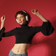 Young woman dancing and listening to music with headphones on red background. Young woman dancing and listening to music with headphones on red background. - PhotoDune Item for Sale