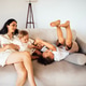 Mother with dark hair sits on a light sofa, joyfully interacting with her two children Mother with dark hair sits on a light sofa, joyfully interacting with her two children - PhotoDune Item for Sale