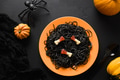 Halloween Italian black pasta decorated horror candy bone in orange plate on black . Halloween Italian black pasta decorated horror candy bone in orange plate on black . - PhotoDune Item for Sale