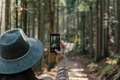 Rear view of woman holding mobile phone, taking photos of moody forest in autumn Rear view of woman holding mobile phone, taking photos of moody forest in autumn - PhotoDune Item for Sale