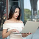 Pretty asian woman student freelancer working on laptop while standing or walking outside a building Pretty asian woman student freelancer working on laptop while standing or walking outside a building - PhotoDune Item for Sale