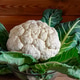 Fresh cauliflower head with green leaves on wood surface Fresh cauliflower head with green leaves on wood surface - PhotoDune Item for Sale