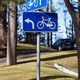 Signs show directions for cyclists in a park with trees and a car parked nearby. Signs show directions for cyclists in a park with trees and a car parked nearby. - PhotoDune Item for Sale