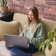 Caucasian young female relaxing on sofa using laptop in cozy brick walled living Caucasian young female relaxing on sofa using laptop in cozy brick walled living - PhotoDune Item for Sale