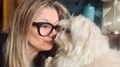 A woman with glasses in a kissing pose with a small white puppy A woman with glasses in a kissing pose with a small white puppy - PhotoDune Item for Sale