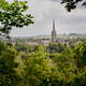 Salisbury Cathedral spire rises above a lush green landscape framed by dense trees. Salisbury, UK Salisbury Cathedral spire rises above a lush green landscape framed by dense trees. Salisbury, UK - PhotoDune Item for Sale