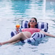 A pregnant woman in sunglasses relaxes on a float in a pool while holding a glass of orange juice. A pregnant woman in sunglasses relaxes on a float in a pool while holding a glass of orange juice. - PhotoDune Item for Sale