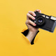 Hand holding retro camera showing yellow paper holes rip. Art collage Hand holding retro camera showing yellow paper holes rip. Art collage - PhotoDune Item for Sale