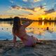 Rear view of young woman in bikini relaxing on a beautiful beach at sunset Rear view of young woman in bikini relaxing on a beautiful beach at sunset - PhotoDune Item for Sale