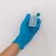 Someones hand with blue latex glove holding disinfectant. Someones hand with blue latex glove holding disinfectant. - PhotoDune Item for Sale