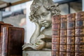 Angelic boy angel statue reading a book between a stack of old books, outside market for sale. Angelic boy angel statue reading a book between a stack of old books, outside market for sale. - PhotoDune Item for Sale