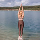 Woman standing in yoga pose with raised arms by lake Woman standing in yoga pose with raised arms by lake - PhotoDune Item for Sale
