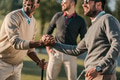 happy multicultural friends shaking hands while playing golf on golf course happy multicultural friends shaking hands while playing golf on golf course - PhotoDune Item for Sale