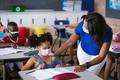 African american female teacher wearing face mask teaching african american girl in class at school African american female teacher wearing face mask teaching african american girl in class at school - PhotoDune Item for Sale