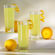 Limoncello Glasses with Curled Lemon Peels and Fresh Lemons on white platforms. Limoncello Glasses with Curled Lemon Peels and Fresh Lemons on white platforms. - PhotoDune Item for Sale