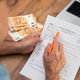 Man filling out W-4 tax form with euro banknotes and laptop on wooden desk. Man filling out W-4 tax form with euro banknotes and laptop on wooden desk. - PhotoDune Item for Sale