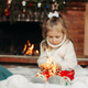 Cute little girl sitting by the fireplace with a Christmas garland.Christmas portrait, cozy style Cute little girl sitting by the fireplace with a Christmas garland.Christmas portrait, cozy style - PhotoDune Item for Sale