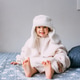 Cute child y on the bed in cozy adult clothes and a hat with earflaps. Emotions and home lifestyle Cute child y on the bed in cozy adult clothes and a hat with earflaps. Emotions and home lifestyle - PhotoDune Item for Sale