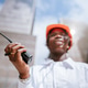 Focused black woman in helmet standing with walkie talkie in daylight near buildings Focused black woman in helmet standing with walkie talkie in daylight near buildings - PhotoDune Item for Sale
