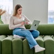 Young woman with cup in hands using laptop computer sitting on sofa at home Young woman with cup in hands using laptop computer sitting on sofa at home - PhotoDune Item for Sale