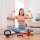 Fit woman showing strong arms after home workout, sitting on yoga mat with kettlebell Fit woman showing strong arms after home workout, sitting on yoga mat with kettlebell - PhotoDune Item for Sale